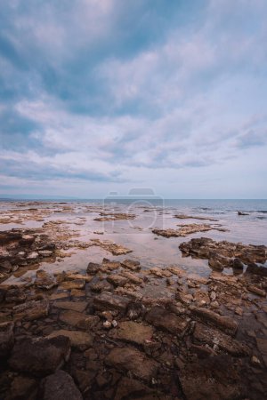 Marzameni, Sicilia, Italia - 16 de marzo de 2022: Vista al mar con playa rocosa y cielo con nubes, vertical