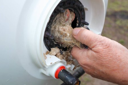 Sacar un calentador eléctrico de la caldera o calentador de agua para eliminar los residuos de cal en él como parte de un mantenimiento.