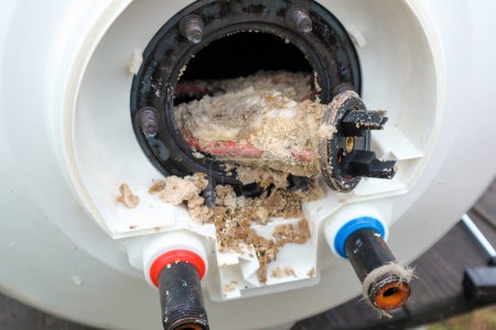 Sacar un calentador eléctrico de la caldera o calentador de agua para eliminar los residuos de cal en él como parte de un mantenimiento.