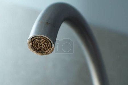 Photo for Selective focus on hard water deposit. Dirty faucet aerator with limescale, calcified shower water tap with lime scale in the kitchen, close up. A heavily calcified faucet - Royalty Free Image