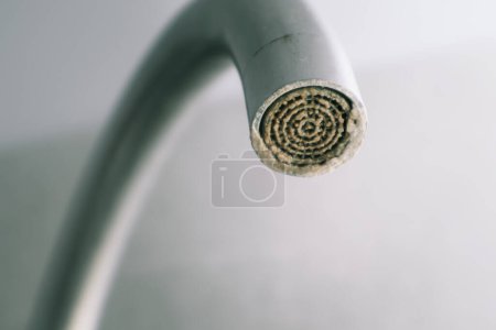 Téléchargez les photos : Concentration sélective sur le dépôt d'eau dure. Aérateur de robinet sale avec calcaire, robinet d'eau de douche calcifiée avec calcaire dans la cuisine, fermer. Un robinet fortement calcifié - en image libre de droit