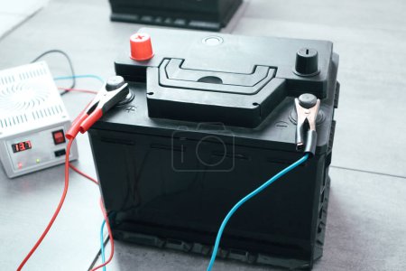 Foto de Battery car charge concept. Charging electric power, energy to accumulator or dead battery. Portable charger, positive negative clamp, red and blue cable wire. - Imagen libre de derechos