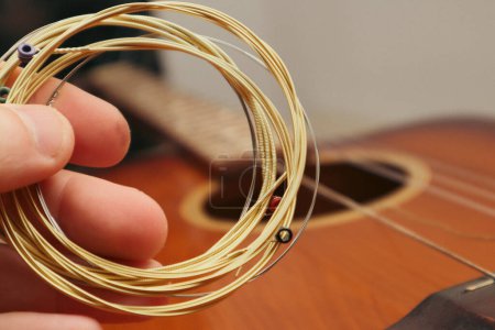 Téléchargez les photos : Le musicien remplace les nouvelles cordes de guitare. La main de l'homme tenant de nouvelles cordes de musique. - en image libre de droit