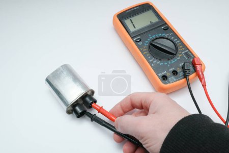 Photo for Diagnostics repair of microwave oven. The hands of the master checking the high-voltage power capacitor and magnetron with multimeter - Royalty Free Image