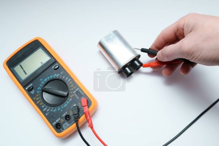 Diagnostics repair of microwave oven. The hands of the master checking the high-voltage power capacitor and magnetron with multimeter