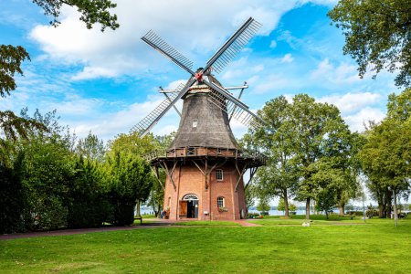 Antiguo molino de viento en el parque termal con gran árbol, Bad Zwischenahn, Baja Sajonia, Alemania