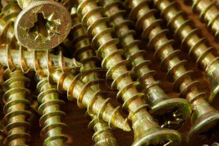 photo of bronze-colored screws close-up, many screws in a group , macro screws , construction background abstraction.