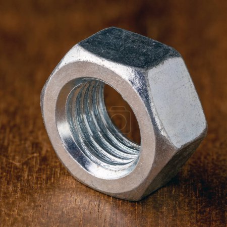 an iron nut photographed in close-up on a dark brown wooden tabletop