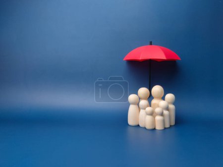 Photo for A family of wooden dolls are hiding under a red umbrella, protecting wooden peg dolls, planning, saving families, preventing risks and crises, health care and insurance concepts. - Royalty Free Image