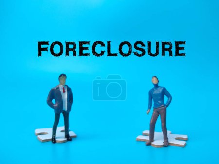 Photo for The two miniature people with the word FORECLOSURE on blue background. - Royalty Free Image