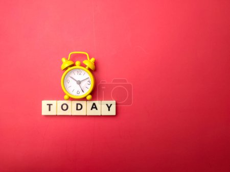 Téléchargez les photos : Yellow alarm clock with the word TODAY on a red background. - en image libre de droit