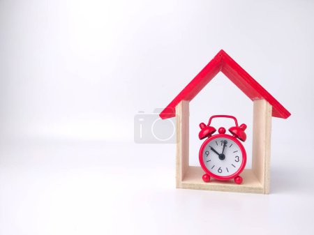 Foto de Reloj despertador y casa de juguete sobre fondo blanco con espacio para copiar. - Imagen libre de derechos