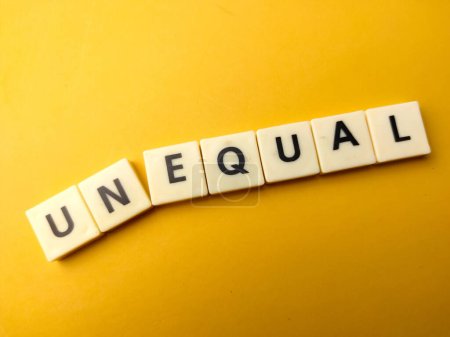 Photo for Toy word with the word UNEQUAL on yellow background - Royalty Free Image