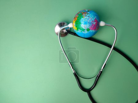 Foto de Estetoscopio y globo terrestre sobre un fondo verde. Salud y concepto médico. - Imagen libre de derechos