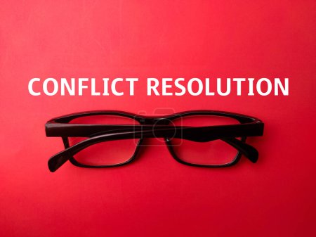 Schwarze Brille mit dem Wort CONFLICT RESOLUTION auf rotem Hintergrund