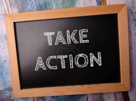 Photo for Wooden black board with the word TAKE ACTION on a wooden background - Royalty Free Image
