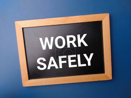 Téléchargez les photos : Panneau en bois noir avec le mot WORK SAFELY sur fond bleu. - en image libre de droit