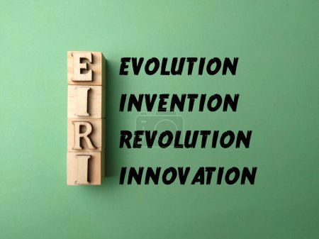 wooden block and word with word EVOLUTION INVENTION REVOLUTION INNOVATION on green background.