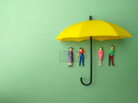 Foto de El paraguas amarillo protegía a una mujer pequeña contra un fondo verde. El concepto de seguro de autoprotección. - Imagen libre de derechos