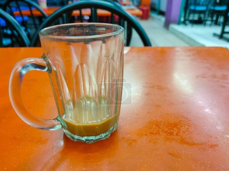 Téléchargez les photos : Un verre de boisson vide teh tarik est sur la table dans un restaurant. - en image libre de droit