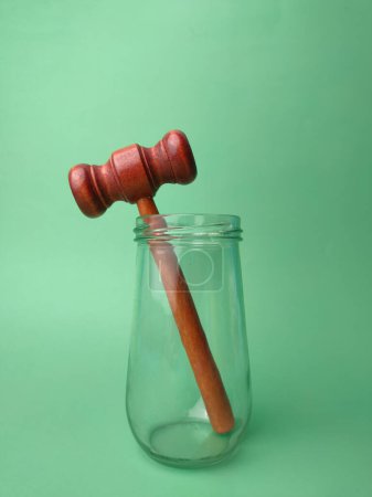 Foto de Martillo de madera en tarro de vidrio sobre un fondo verde con espacio para copiar. - Imagen libre de derechos