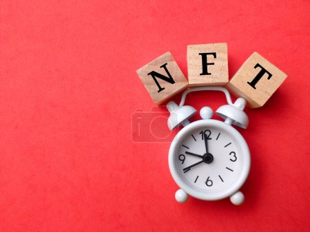 Foto de Reloj despertador blanco vista superior con texto NFT sobre fondo rojo. - Imagen libre de derechos