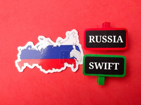 Top view Bandera de Rusia y tablero de madera con texto RUSSIA SWIFT sobre fondo rojo.