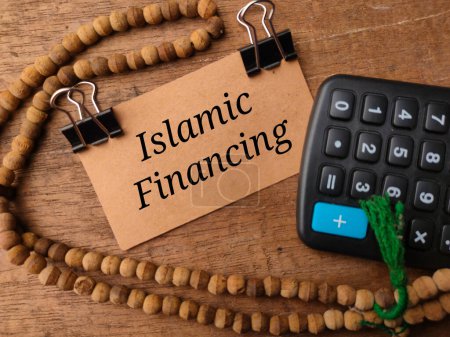 Foto de Vista superior de la cuenta de oración, calculadora y tarjeta marrón con texto Islamic Financing sobre fondo de madera. - Imagen libre de derechos