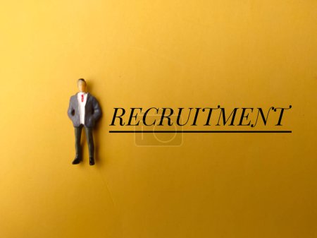 Top view miniature people with text RECRUITMENT on yellow background.