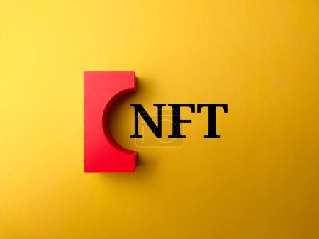 Draufsicht farbiger Holzblock mit Text NFT auf gelbem Hintergrund.