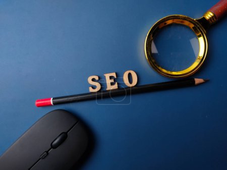 Photo for Top view pencil and word SEO with black magnifying glass on a blue background - Royalty Free Image