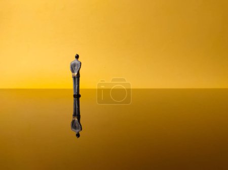 Miniature people with reflection on a yellow background with copy and text space. Business concept