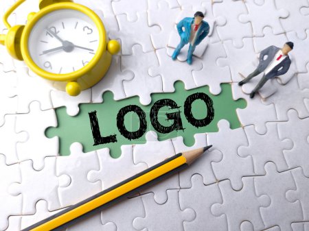 Top view clock,pencil and miniature people with text LOGO on a white puzzle background
