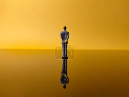 Miniaturmenschen mit Reflexion auf gelbem Hintergrund. Geschäftskonzept