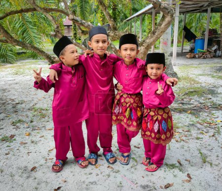 Téléchargez les photos : Perak, Malaisie, 10 avril 2024 : Quatre garçons vêtus de vêtements malais posant pour des photos avant de sortir pour célébrer le matin de Hari Raya - en image libre de droit