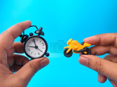 Mano sosteniendo reloj y motocicletas juguetes sobre un fondo azul. Concepto de seguro.