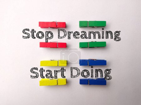 Photo for Top view colored wooden clips with text Stop Dreaming Start Doing on a white background. - Royalty Free Image