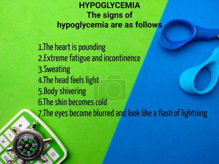 Top view compass and calculator with text the signs of hypoglycemia on a colorful background. Healthcare concept.