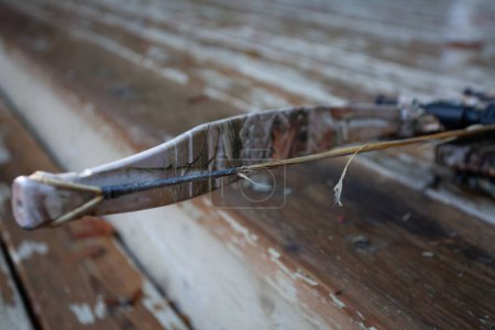 A frayed, worn out, broken bowstring that will need to be replaced.  This is general maintenance on compound and crossbows, and is very important to keep in good repair. Shallow depth of field.