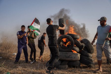Foto de Los palestinos se manifiestan en la frontera de la Franja de Gaza. 25 de octubre de 2022, Franja de Gaza, Palestina: Un gran número de jóvenes palestinos queman neumáticos de goma En la frontera oriental de la ciudad de Gaza, como expresión de su ira contra el ejército israelí - Imagen libre de derechos
