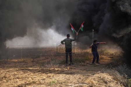 Foto de Los palestinos se manifiestan en la frontera de la Franja de Gaza. 25 de octubre de 2022, Franja de Gaza, Palestina: Un gran número de jóvenes palestinos queman neumáticos de goma En la frontera oriental de la ciudad de Gaza, como expresión de su ira contra el ejército israelí - Imagen libre de derechos