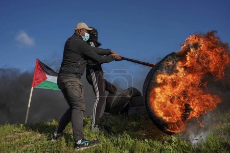 Photo for Palestinians demonstrate on the borders of the Gaza Strip. February 22, 2023, Gaza, Palestine: Palestinian youth set fire to rubber tires on the eastern borders of the Gaza Strip - Royalty Free Image