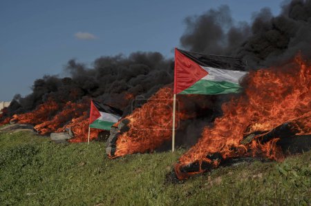 Foto de Los palestinos se manifiestan en las fronteras de la Franja de Gaza. 22 de febrero de 2023, Gaza, Palestina: Jóvenes palestinos incendian neumáticos de goma en las fronteras orientales de la Franja de Gaza - Imagen libre de derechos