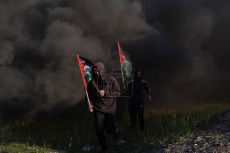 Foto de Los palestinos se manifiestan en las fronteras de la Franja de Gaza. 22 de febrero de 2023, Gaza, Palestina: Jóvenes palestinos incendian neumáticos de goma en las fronteras orientales de la Franja de Gaza - Imagen libre de derechos