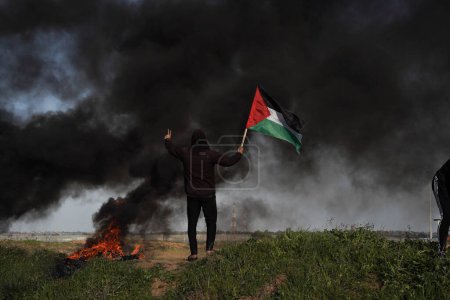 Photo for Palestinians demonstrate on the borders of the Gaza Strip. February 22, 2023, Gaza, Palestine: Palestinian youth set fire to rubber tires on the eastern borders of the Gaza Strip - Royalty Free Image