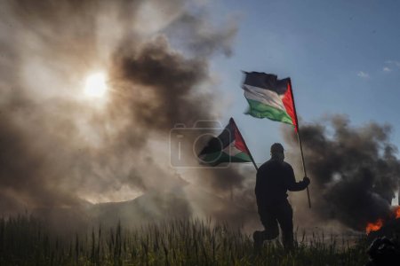 Téléchargez les photos : Palestinians demonstrate on the borders of the Gaza Strip. February 22, 2023, Gaza, Palestine: Palestinian youth set fire to rubber tires on the eastern borders of the Gaza Strip - en image libre de droit