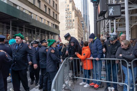 Téléchargez les photos : St. Patrick & # 39 ; s Day Parade à New York. 17 mars 2023, New York, New York, USA : Un membre de la FDNY franchit la barricade pour participer au défilé de la Saint Patrick & # 39 le long de la 5e Avenue le 17 mars 2023 à New York. - en image libre de droit