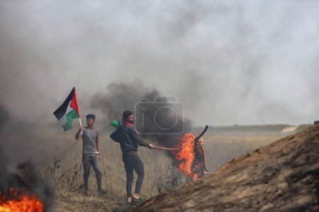 Foto de (INT) Jóvenes palestinos incendian neumáticos de goma en las fronteras de la Franja de Gaza. 5 de abril de 2023, Gaza, Palestina: Decenas de jóvenes palestinos incendian neumáticos de goma en las fronteras orientales de la Franja de Gaza - Imagen libre de derechos