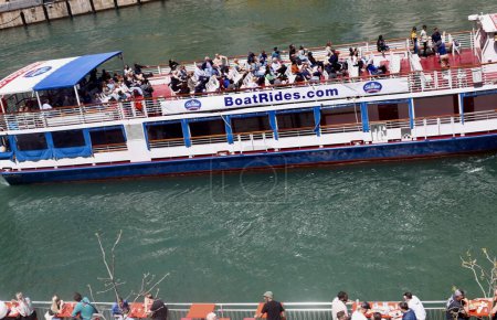 Photo for (NEW) Chicago River Walk and its Attractions. May 05, 2023, Chicago, Illinois, USA: Tourists flock Chicago River Walk enjoying the Spring sunny weather on boat cruise, some canoeing, eating food along side the river with Trump building - Royalty Free Image