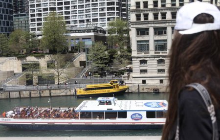 Foto de (NUEVO) Chicago River Walk and its Attractions. Mayo 05, 2023, Chicago, Illinois, USA: Los turistas acuden a Chicago River Walk disfrutando del clima soleado de primavera en un crucero en barco, algo de piragüismo, comiendo comida junto al río con la construcción de Trump - Imagen libre de derechos